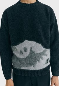 Maglione a maglia grigio scuro con un design astratto grigio chiaro al centro; presenta un colletto e orlo a coste. Tessuto morbido e testurizzato.