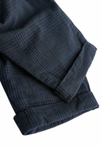 Dunkelblauer Karostoff mit; glatter Textur, umgeschlagenen Bündchen und vertikalen Linien, die subtile Musterdetails auf dem Baumwollmaterial erzeugen.