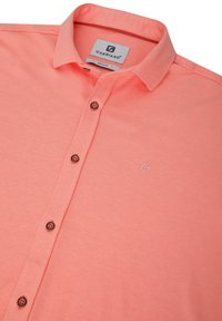 Camicia a maniche corte color corallo realizzata in tessuto morbido, con colletto button-down, cinque bottoni scuri e un logo ricamato sul petto.