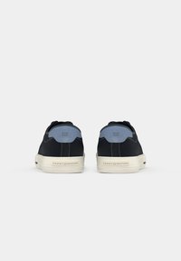 Baskets en tissu noir avec un accent sur le talon bleu clair. Semelle en caoutchouc avec logo de la marque visible, design minimaliste et couture contrastante.