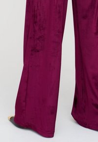 Velours-Hose mit weitem Bein in einem satten Burgunderrot, mit weicher Textur und elegantem Finish sowie einem dezenten Schimmer.
