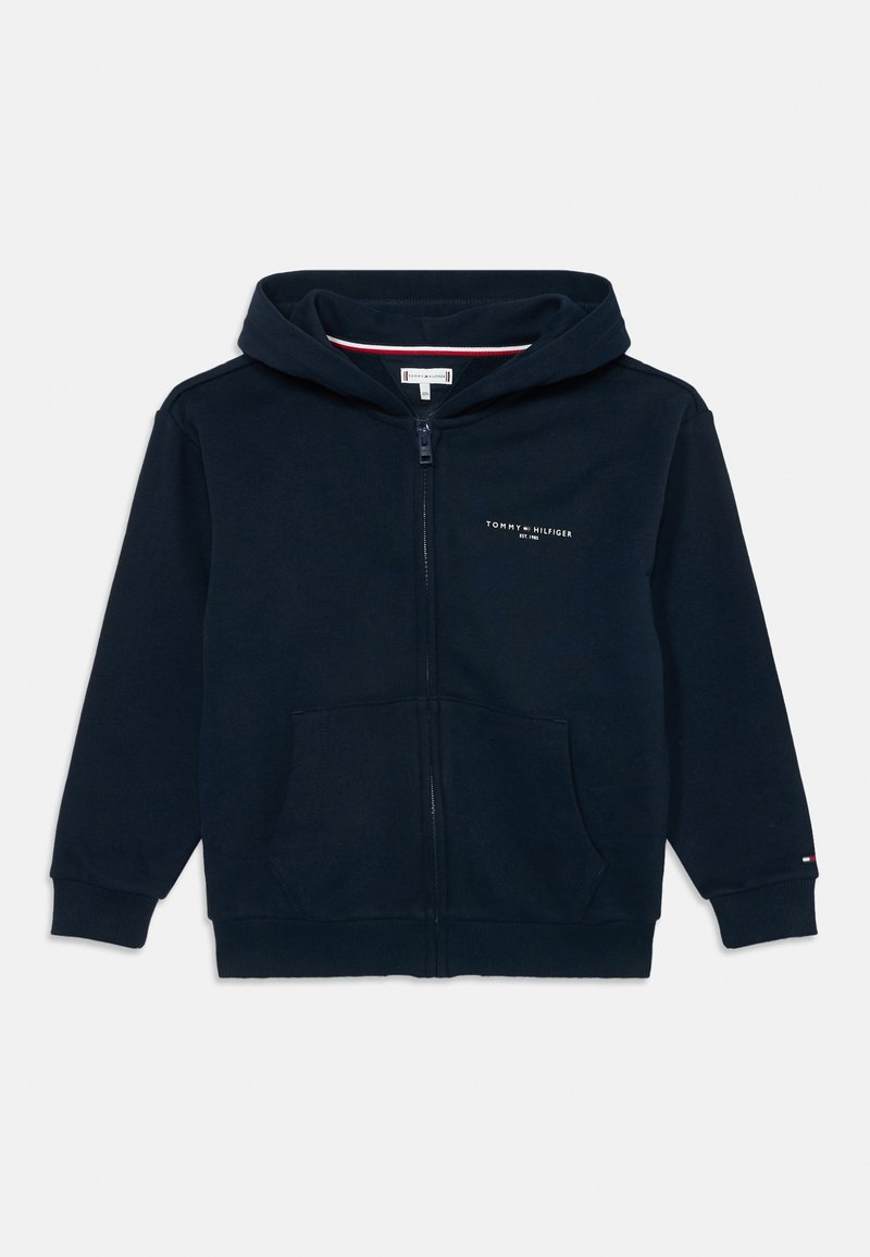 Mornarsko plava dukserica s patentnim zatvaračem, prednjim džepovima, rebrastim manžetama, malim Tommy Hilfiger logotipom na prsima i rukavu, te kapuljačom.