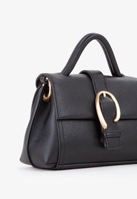 Borsa a mano in pelle nera con finitura texturizzata, accessori in oro, manico arrotondato e chiusura a patta. Design compatto e strutturato.