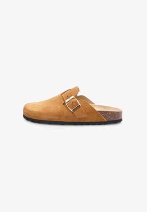 Mule in suede marrone con cintura a fibbia, forma curvata, superficie testurizzata e plantare in sughero. La suola in gomma nera garantisce aderenza e durabilità.