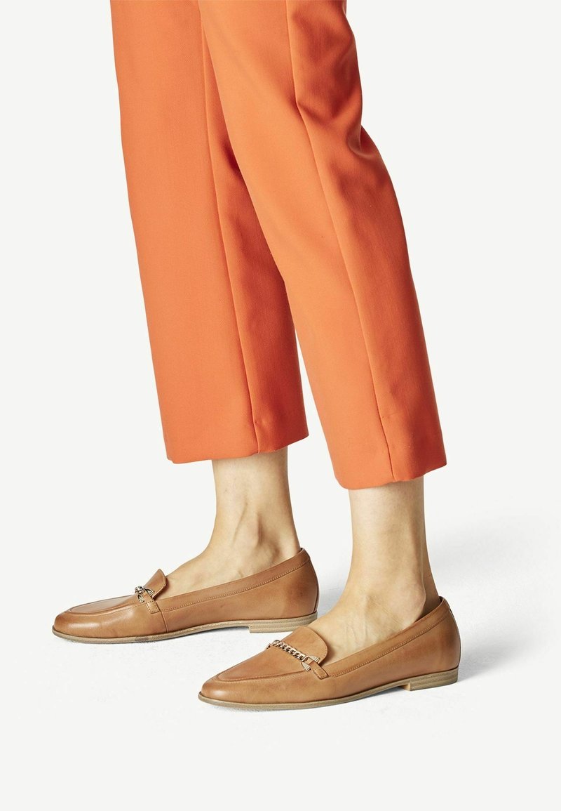 Mocassins en cuir tan avec un accent chaîne, semelle plate et bout rond, associés à un pantalon orange cropped au toucher doux.