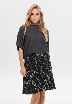 Grijze top met korte mouwen gecombineerd met een zwarte rok met bloempatronen in pastelkleuren. Zacht materiaal met een ontspannen pasvorm en een vloeiende uitstraling.