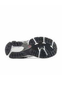 Rubber outsole of a shoe featuring a multi-directional tread pattern, primarily black with gray and white accents, designed for traction.
