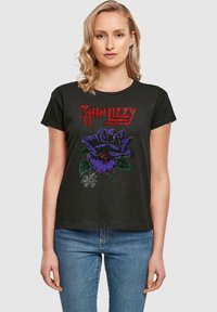 Černé bavlněné tričko s grafickým vyobrazením fialové růže a červeným textem "Thin Lizzy". Krátké rukávy, kulatý výstřih, volný střih.