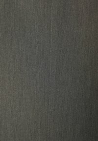 Närmre bild av mörkgrått tyg med en vertikal söm sydd ner i mitten, som visar en fin diagonalt vävstruktur.