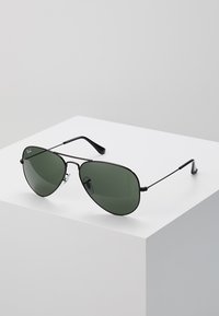 Ochelari de soare de tip aviator, cu cadru subțire și lentile de culoare verde închis. Dispune de pernițe pentru nas ajustabile și brațe elegante.