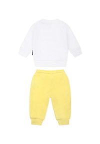 Dwuczęściowy strój składający się z białego bawełnianego swetra z długim rękawem i okrągłym dekoltem, zestawiony z żółtymi bawełnianymi joggerami z elastycznym pasem.