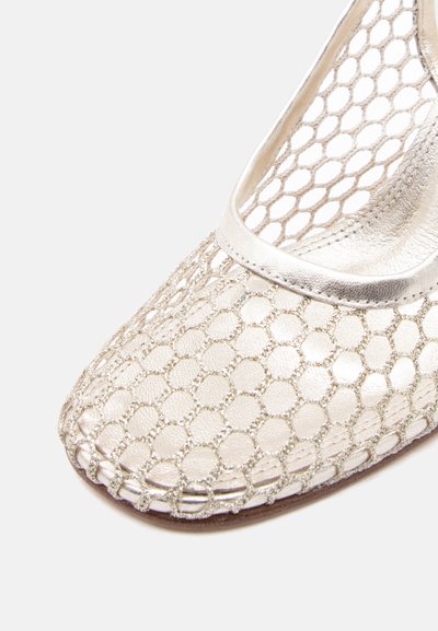 Κοντινό πλάνο ασημένιου πλατφόρμας παπουτσιού με επίστρωση από δίχτυ ψαρέματος και λείο δερμάτινο επένδυμα στην περιοχή των δαχτύλων.