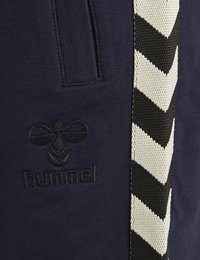 Marina sweatpants med en texturerad logotypapplikation och en sidremsa med ett svart och vitt zigzag-mönster. Inkluderar en sidoficka.