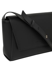 Fekete, téglalap alakú bőr válltáska állítható pánttal és fedélzárással, elülső oldalán diszkrét, bélyegzett márkanevével.