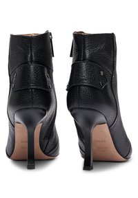 Czarne skórzane botki za kostkę z teksturowanym wykończeniem, wysokimi obcasami typu stiletto, bocznym zamkiem błyskawicznym oraz ozdobnym mankietem z metalowymi akcentami.