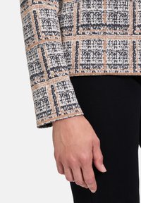 Trui met een gestructureerd, geweven ontwerp met een ruitpatroon in zwart, wit en oranje. Lange mouwen met een contrasterende zoom en manchetten.