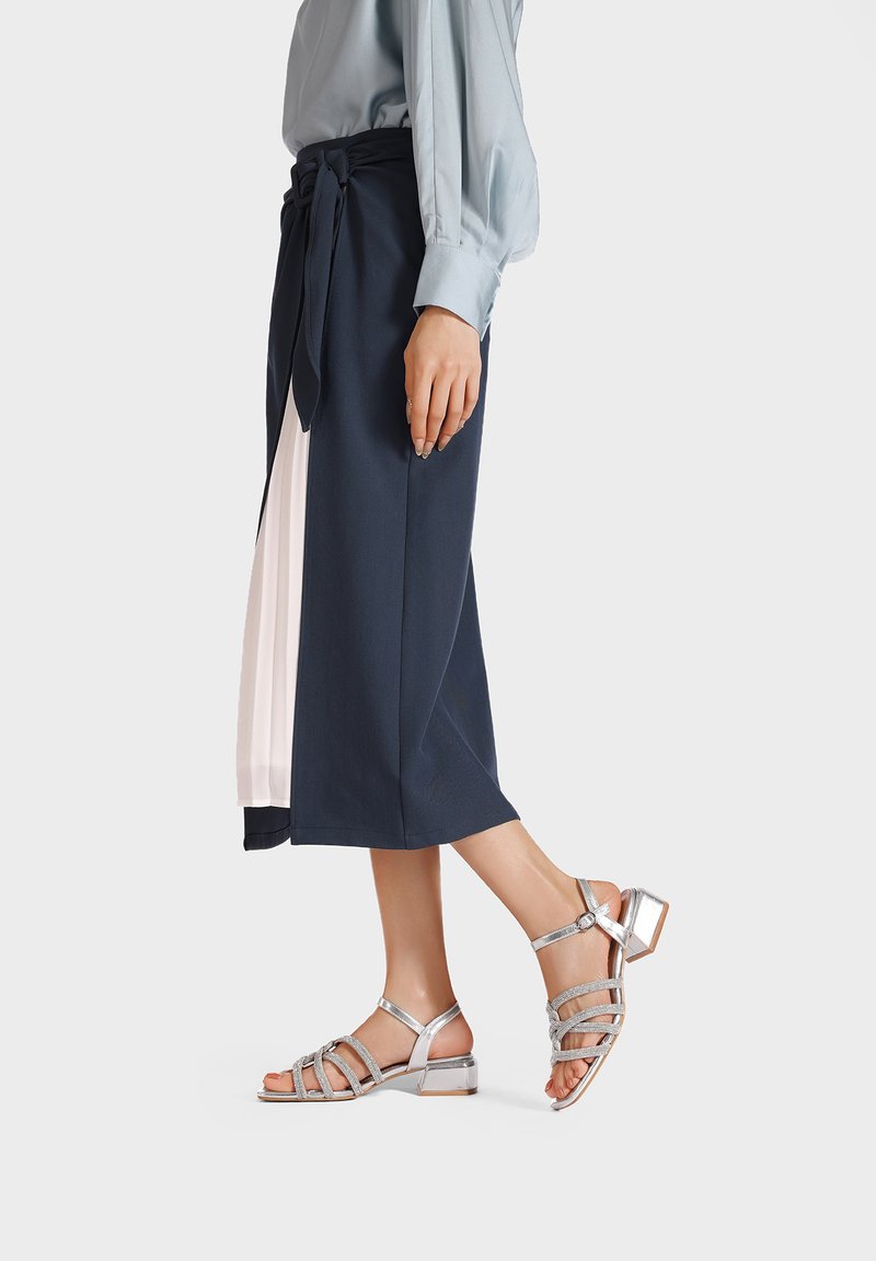 Gonna midi blu navy con vita legata e un pannello rosa pallido. Sandali silver con tacco a blocco e cinturini testurizzati.