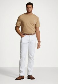 Camiseta de manga curta bege, jeans brancos, cinto de couro castanho e sapatos castanhos. Design simples, sem padrões ou logótipos visíveis.