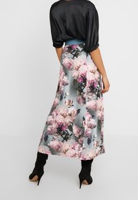 Květinová maxi sukně se světle modrým pozadím, zdobená velkými růžovými růžemi a zelenými listy. Nosit s černým saténovým topem a černými botami na podpatku.