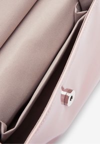 Różowa torba z lakierowanej skóry ze wnętrzem pokrytym beżową tkaniną. Posiada magnetyczne zapięcie oraz liczne przegrody do organizacji.