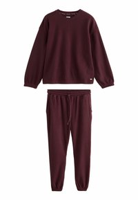 Burgundy loungewear szett, textúrált anyagból készült, amely tartalmaz egy hosszú ujjú, kerek nyakú pulóvert és elasztikus derekú, zsinórral ellátott nadrágot.