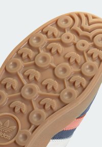 Gumová podrážka s texturovaným vzorem, obsahující kruhové a listové vroubky. Barva je světle hnědá, poskytující přilnavost a odolnost.