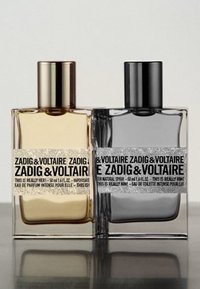Bouteilles de parfum Zadig & Voltaire : verre rectangulaire transparent avec des bouchons métalliques dorés et noirs, étiquettes texturées et sections de couleur distinctes - doré et noir.