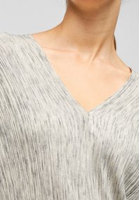 Light grey, textured knit top with a V-neckline and short sleeves, featuring subtle vertical stripes in darker grey tones.