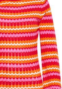 Maglione a coste con strisce a zigzag in rosso, rosa, arancione e bianco. Maniche lunghe con design aderente e tessuto testurizzato.