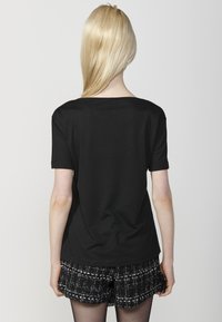 Camiseta negra de manga corta con cuello redondo, fabricada en tela suave, con un corte relajado y sin patrones ni adornos visibles.