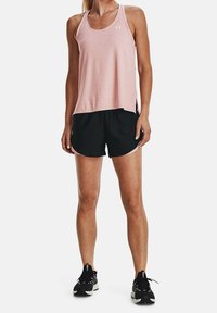 Top deportivo sin mangas de color rosa claro combinado con pantalones cortos negros que cuentan con acentos rosas contrastantes. Usado con zapatos deportivos negros.