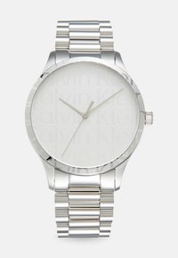 Silver stainless steel watch with a round face, showcasing an embossed logo, minimalist design, and a link bracelet.