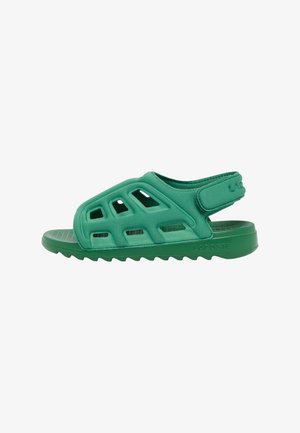 Sandalia verde Lacoste con parte superior perforada, correa trasera ajustable y suela texturizada para uso casual.