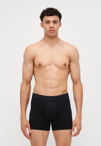 Fekete boxer alsónadrág rugalmas anyagból, széles gumis derékkal és kényelmes, testhezálló fazonnal. Minimalista stílusú, minta nélkül.