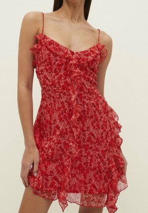 Rode jurk met bloemmotief, ruches als afwerking, dunne bandjes, lichtgewicht stof en een uitlopende zoom. Heeft een getailleerd lijfje en een zachte textuur.