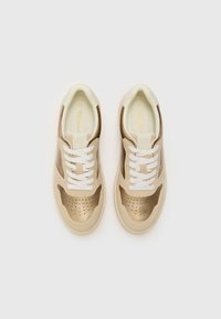 Sneakers with a beige and gold color scheme, featuring a smooth leather upper, perforated details, and white laces. Distinctive design accents.