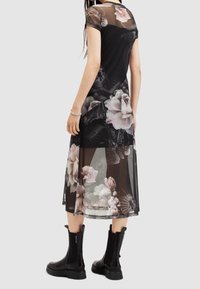 Black floral mesh dress with short sleeves, featuring large pink and white roses. Styled with chunky black boots, creating a layered look.