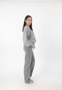 Grijze gebreide trui met lange mouwen en een hoge hals, gecombineerd met grijze rechte jeans. Soepele textuur en relaxte pasvorm.