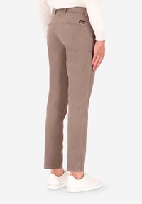 Pantaloni chino marrone chiaro realizzati in tessuto morbido, con vestibilità slim, tasche posteriori e un'etichetta con logo sulla cintura.