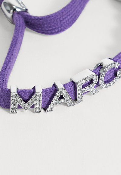 Μωβ πλεκτό βραχιόλι με ασημένια γράμματα διακοσμημένα με διάφανα κρύσταλλα που σχηματίζουν μέρος της λέξης "MARC."