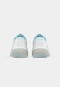 Une paire de baskets blanches et bleu clair vue de l'arrière, montrant des semelles grises et des détails perforés au niveau du talon sur un fond blanc uni.