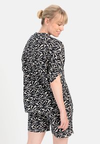 Sorte og hvide mønstrede loungewear sæt bestående af en kortærmet top og shorts, lavet af letvægtsstof med en afslappet pasform.