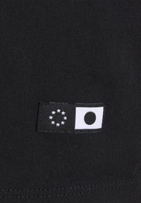 Tessuto nero con un piccolo etichetta che presenta un design a bandiera, inclusi un cerchio e stelle, che rappresentano l'Europa e un altro emblema circolare.