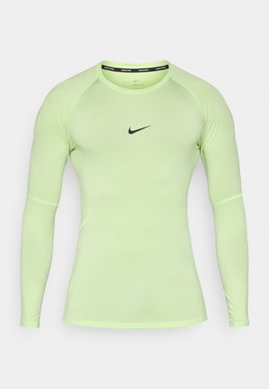 Chemise Nike Pro à manches longues en tissu vert néon, avec une coupe ajustée, un col rond et un logo Nike noir sur la poitrine.