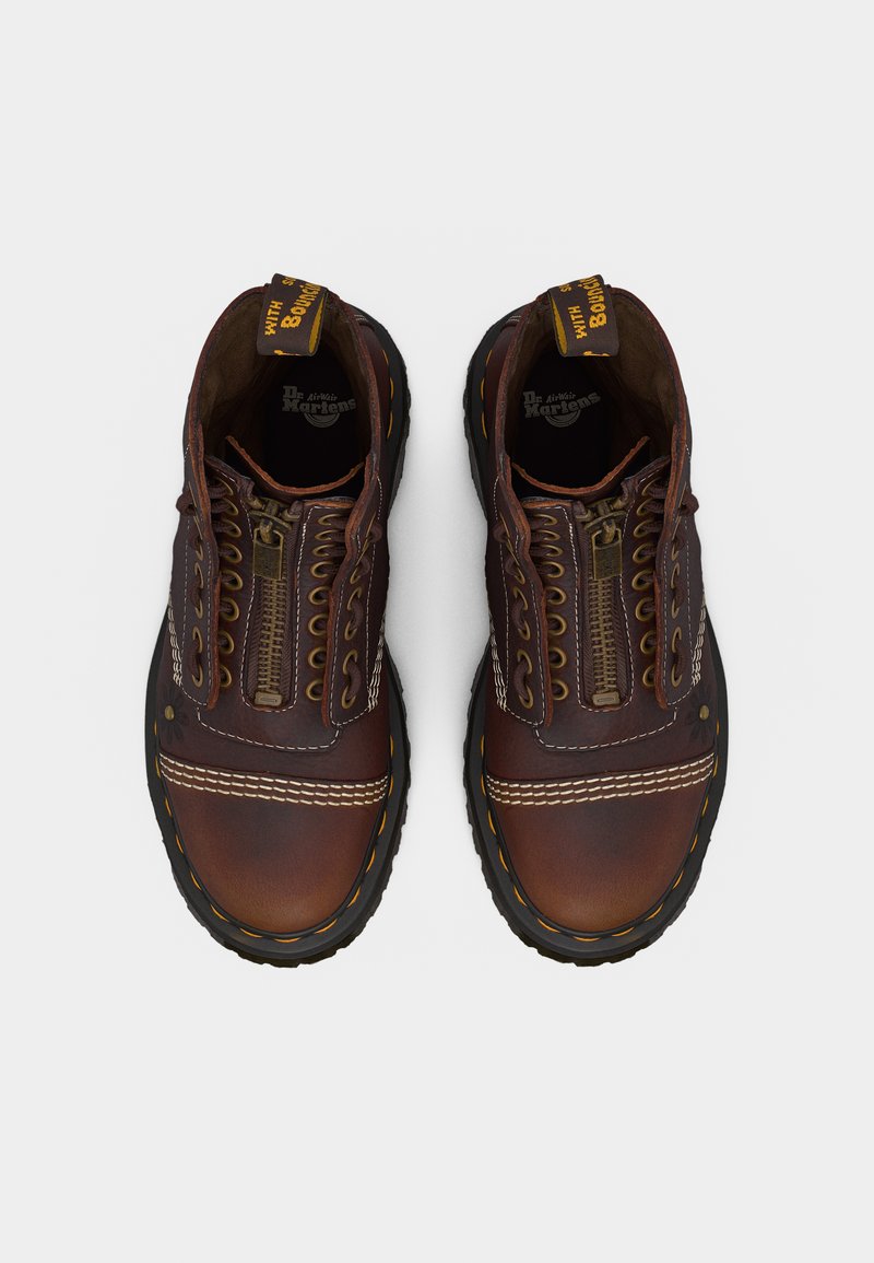 Pair of brown leather lace-up boots with front zippers and yellow stitching, viewed from above on a light background.