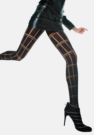 Jambes en collants noirs avec un motif à carreaux beiges, portant une mini-jupe en cuir noir et des bottines noires à talons hauts, une jambe levée en plein pas.