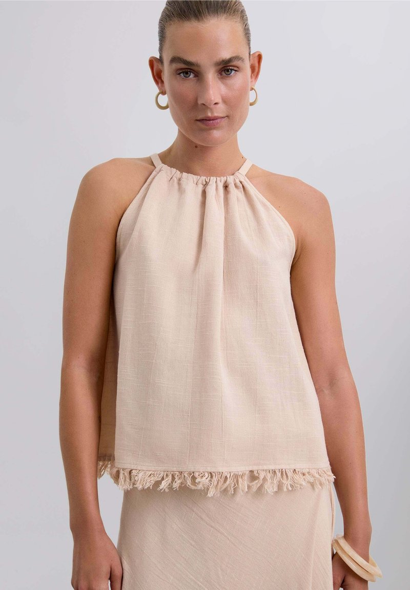 Top halter beige claro con escote fruncido y detalle de flecos en el dobladillo, hecho de una tela texturizada. Diseño sencillo, sin mangas.