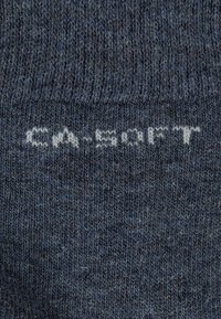 Calzini lavorati a maglia di colore blu scuro con una consistenza morbida, con la scritta "CA-SOFT" stampata in grigio chiaro. Design semplice, colore uniforme.