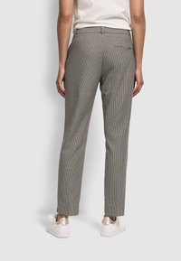 Grijze geblokte broek met een slim fit, voorzien van een tailleband en een enkele achterzak, gecombineerd met witte schoenen accentueert door goud.