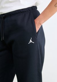 Marineblaue Jogginghose mit Kordelzug an der Taille und Seitentasche. Mit weiß gesticktem Jumpman-Logo am linken Oberschenkel. Weiches Material, entspannte Passform.